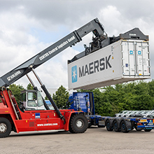 Roter LKW mit Krahn, der einen Container hebt